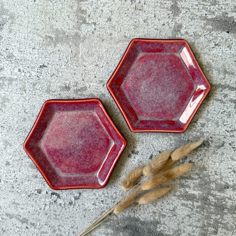 Two red hexagon trinket dishes on textured background.