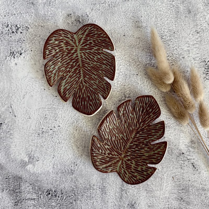 Two brown leaf-shaped dishes with pampas stems.