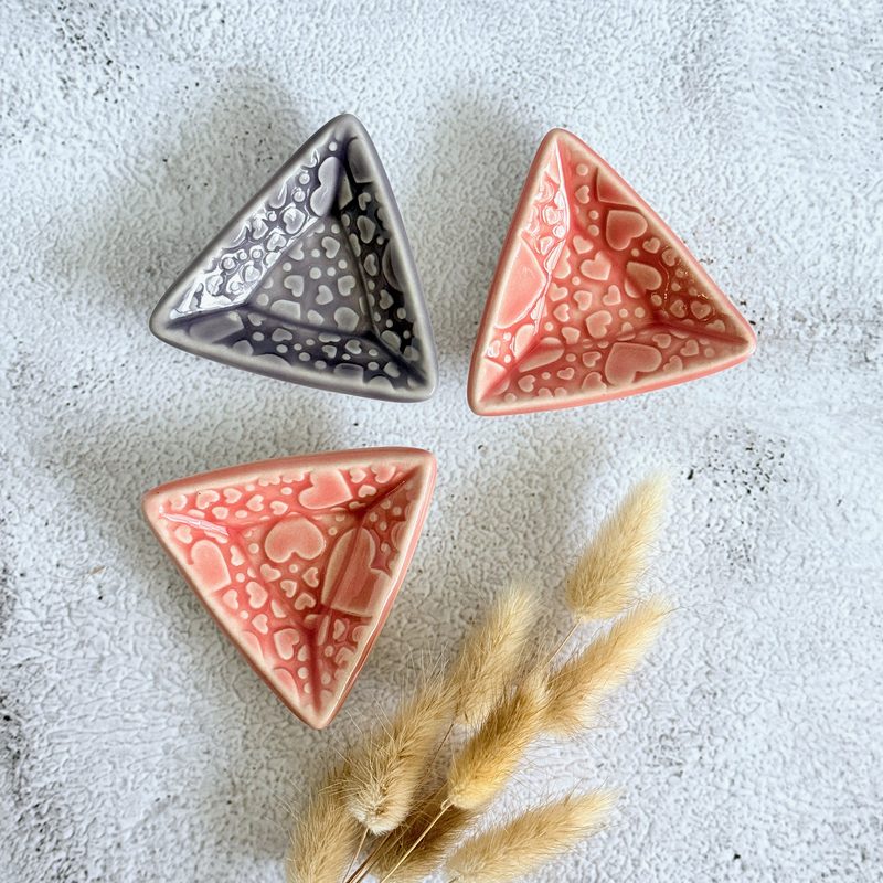 Three triangular trinket dishes in pink and charcoal.