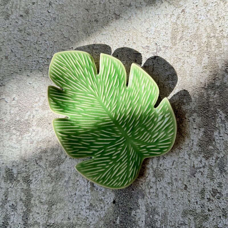 Small green ceramic dish shaped like a leaf with carved vein texture