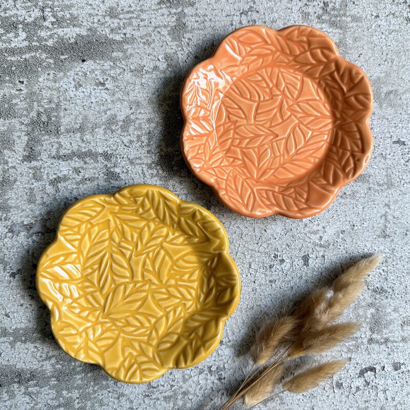 Pair of scalloped ceramic plates in orange and yellow glazes with raised leaf pattern