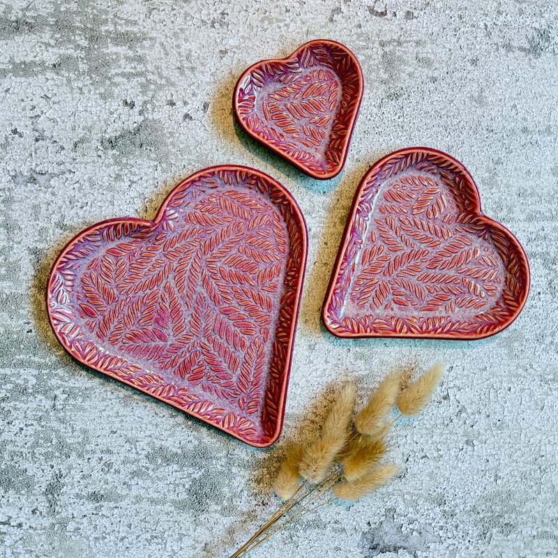 Set of three heart-shaped ceramic trays with carved leaf pattern in rich red and purple glazes